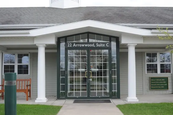 The practice's entrance portico at 22 Arrowwood Drive, with white columns and a bench.