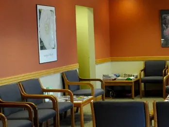 The practice's waiting room, with upholstered chairs and framed prints on warm orange walls.